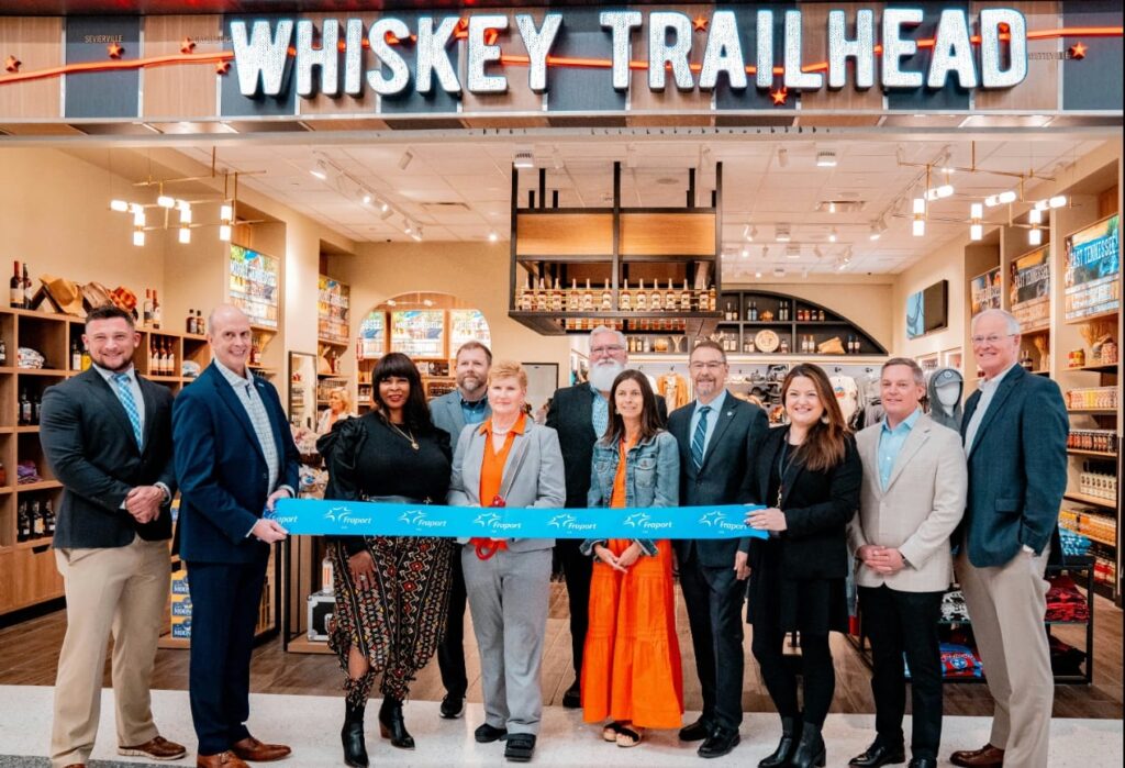 WH Smith North America executives standing in front of the Whiskey Trailhead shop for the ribbon cutting.